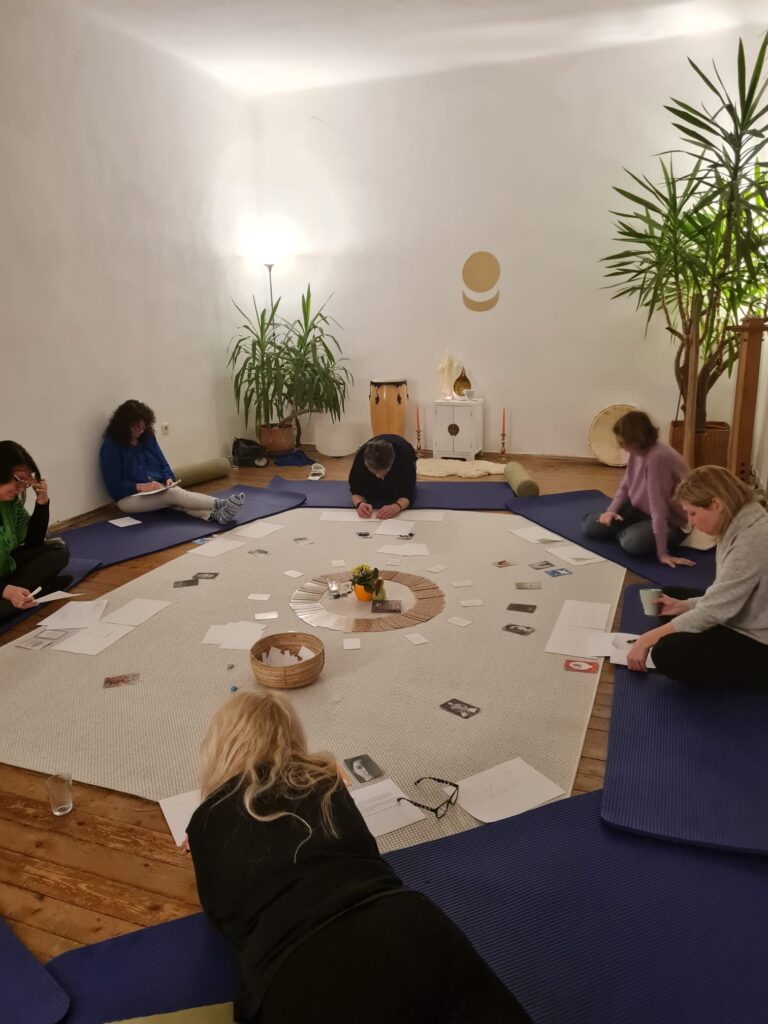 Ein Kreis aus Matten, Karten und Workshop Teilnehmer/innen am schreiben auf Zettel am Boden